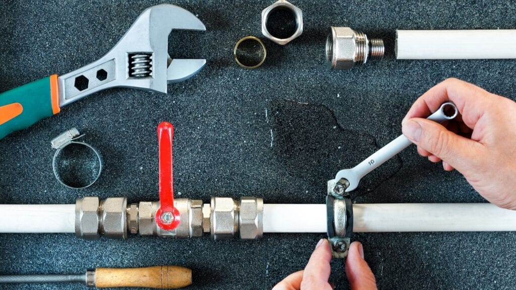 Plumber repairing a pipe valve with an adjustable wrench in Pembroke Pines