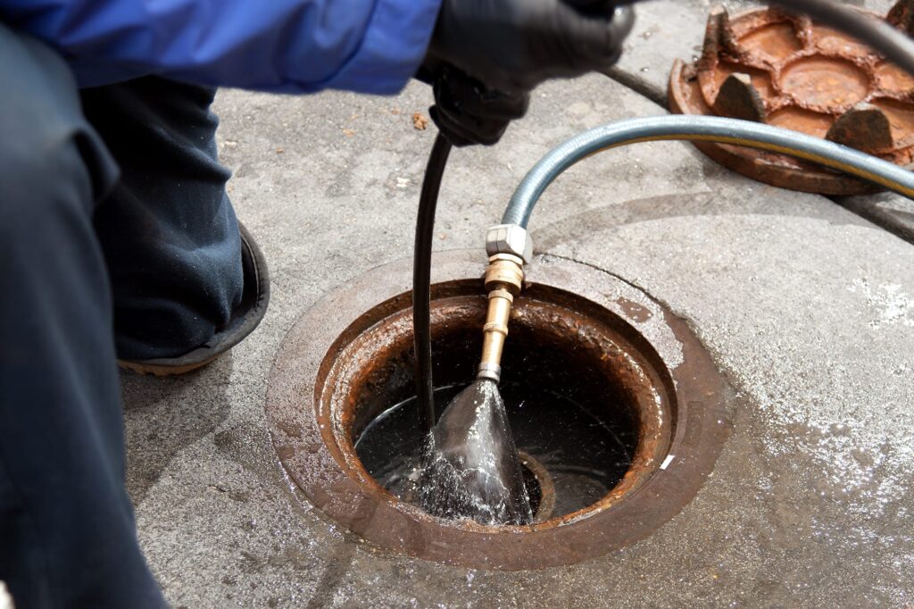 Plumber hydro jetting a sewer line through a manhole in Pembroke Pines