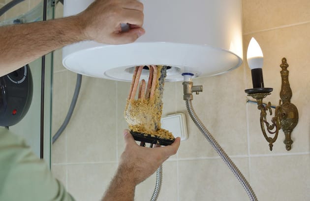 Technician removing mineral buildup from a water heater in Pembroke Pines