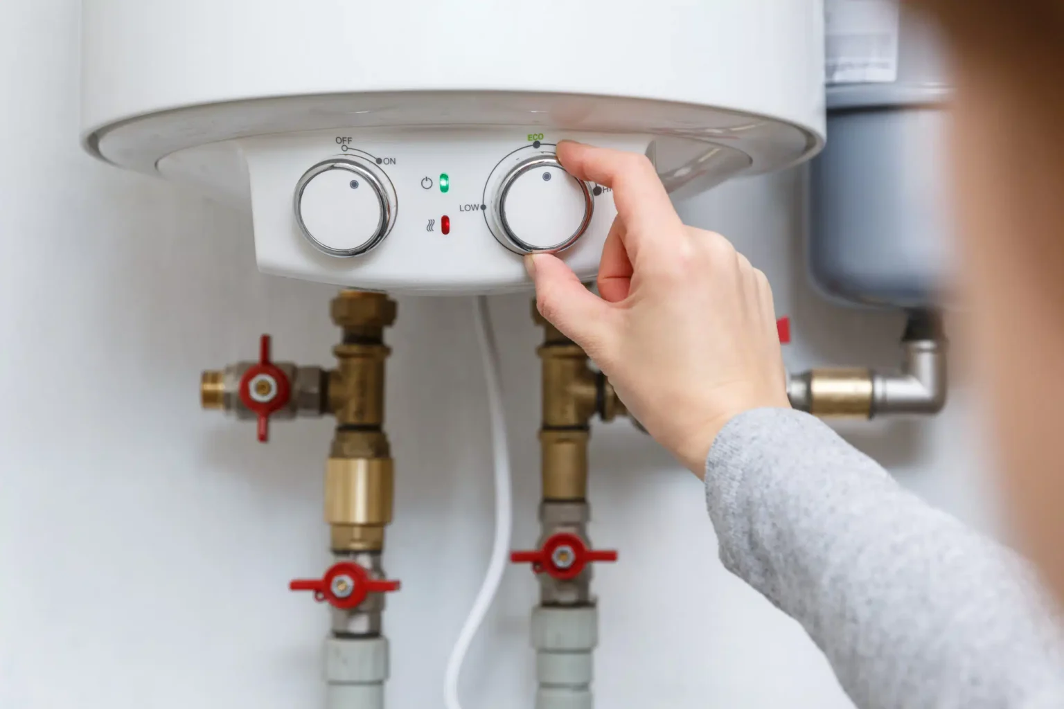 Homeowner adjusting the temperature controls on a water heater in Pembroke Pines